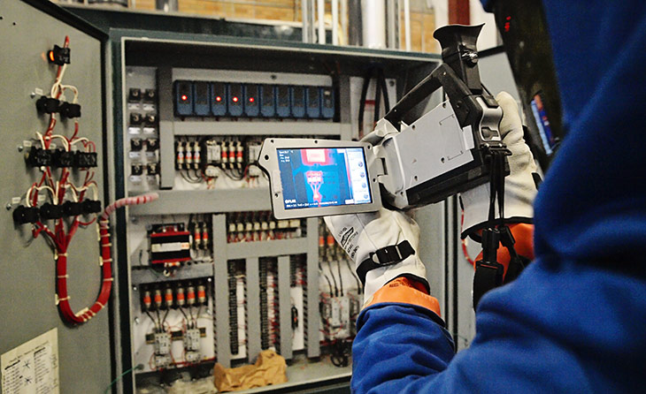 Technician using infrared thermography equipment on an electrical panel